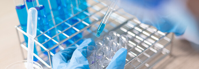 Scientists are carrying blue chemical test tubes to prepare for the determination of chemical...
