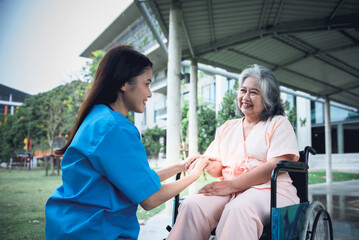 Obraz premium Asian woman doctor holding hands elderly woman patient Which sat on wheelchair to encourage To fight the disease, to elderly health care and osteoporosis concept.