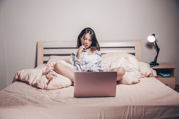a young Asian webcam model girl is sitting in front of a laptop with her legs spread. she communicates and shows her charms. low depth of focus,artistic photo processing