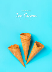 A set of waffle cones for ice cream on a blue background. Top view, vertical.