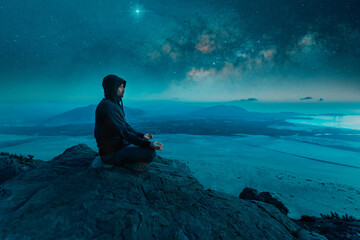 person sitting on the top of the mountain meditating at night with stars and  Milky Way background - obrazy, fototapety, plakaty