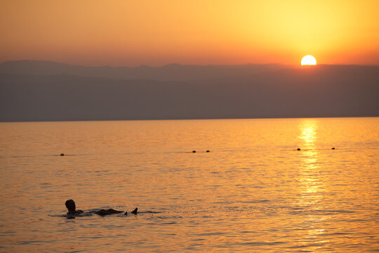 Man floating in the dead sea at sunset, Jordan