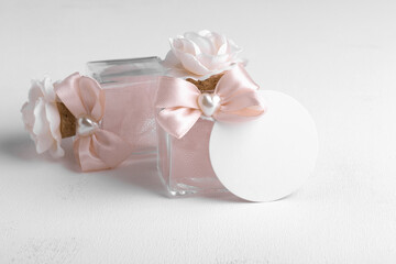 Round gift tag mockup with beige wedding favor on a white background, decorative bottle with favor tag mockup. Wedding favor tag for souvenir, sign for message greeting, close up, element for design