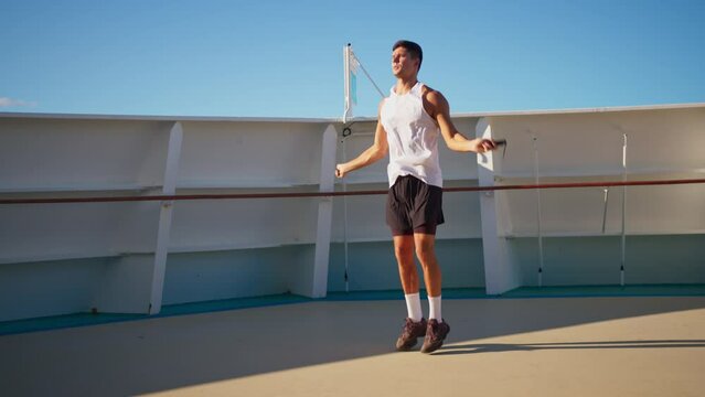 Athletic young man jumping rope outside on cruise ship open deck