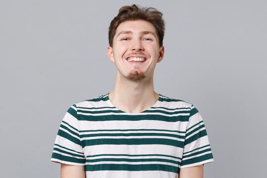Young caucasian cheerful joyful fun cool positive laughing friendly man 20s wearing blue striped t-shirt look camera isolated on plain gray color background studio portrait. People lifestyle concept.