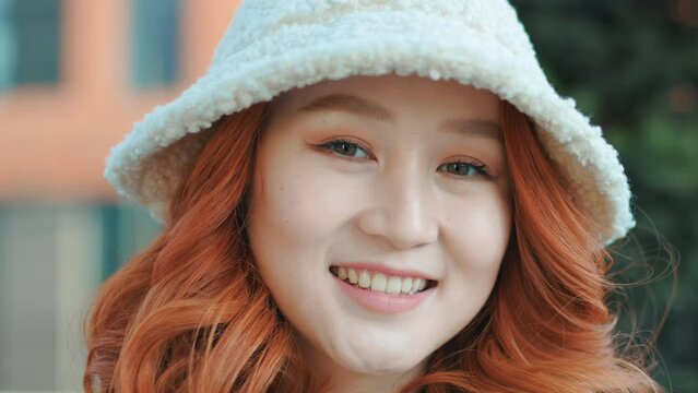 Portrait of a smiling attractive Asian girl with red hair