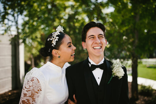 Latina bride and multiracial groom laugh and smile after wedding