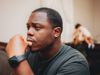 close up of African American or black man at home sitting looking depressed and worried while wife...
