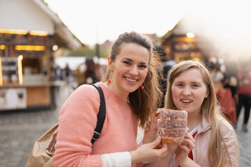 happy modern mother and child at fair in city eating trdelnik