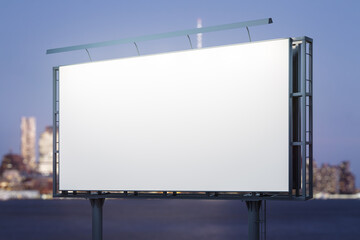 Obraz premium Blank white horizontal billboard on city buildings background at night, perspective view. Mockup, advertising concept