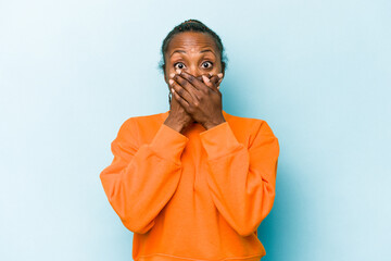 Young african american woman isolated on blue background shocked covering mouth with hands.