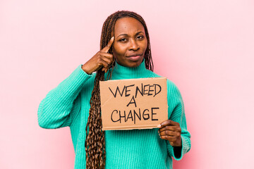 Young African American woman holding we need a change placard isolated on pink background