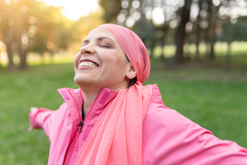 happy mature woman smiling with a pink scarf, symbol against breast cancer, - positive cancer...