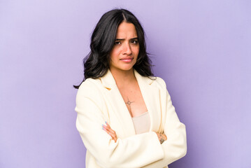 Young hispanic woman isolated on purple background frowning face in displeasure, keeps arms folded.