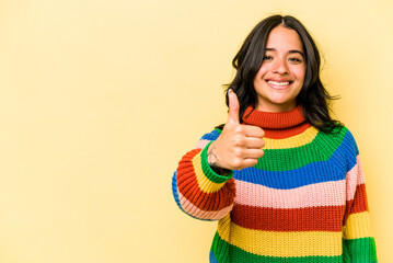 Young hispanic woman isolated on yellow background smiling and raising thumb up