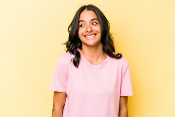 Young hispanic woman isolated on yellow background laughs and closes eyes, feels relaxed and happy.