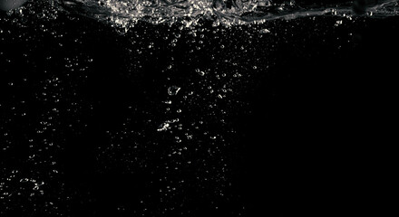 Blurry images of clear transperant soda liquid bubbles splashing or sparkling and moving up in black background for represent the refreshing moments after drink carbonated water.