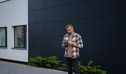 A man works with a tablet in the park near office buildings