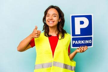 Young hispanic woman holding parking placard isolated on blue background