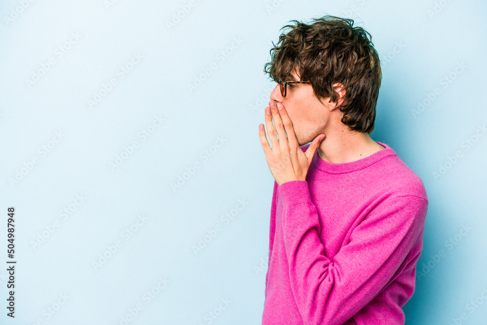 Wall mural young caucasian man isolated on blue background being shocked because of something she has seen.