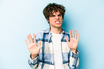 Young caucasian man isolated on blue background rejecting someone showing a gesture of disgust.