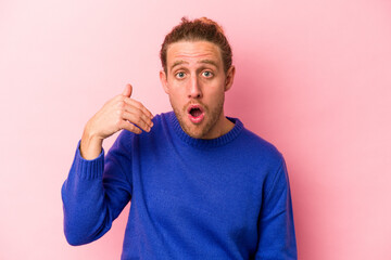 Young caucasian man isolated on pink background laughing about something, covering mouth with hands.