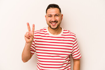 Naklejka premium Young hispanic man isolated on white background showing victory sign and smiling broadly.