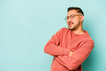 Young hispanic man isolated on blue background smiling confident with crossed arms.