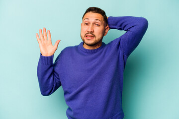 Young hispanic man isolated on blue background screaming with rage.