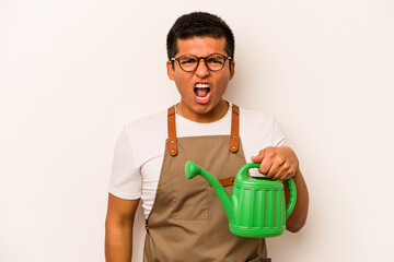 Young gardener hispanic man holding a watering can isolated on white background screaming very...