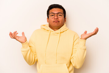 Young hispanic man isolated on white background doubting and shrugging shoulders in questioning...