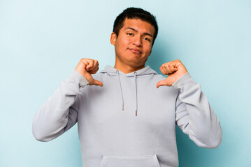Young hispanic man isolated on blue background feels proud and self confident, example to follow.