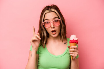Young caucasian woman holding an ice cream isolated on pink background having an idea, inspiration concept.