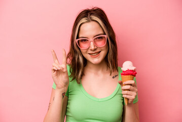 Young caucasian woman holding an ice cream isolated on pink background showing number two with fingers.