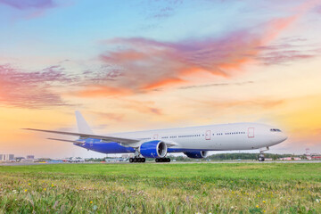 Heavy wide-body long-haul jet aircraft taxis to the runway for takeoff, against the backdrop of a beautiful dawn sunset sky.