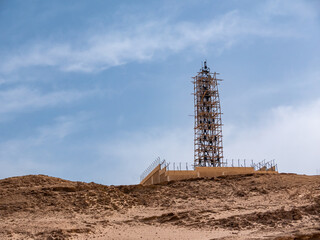 A radar tower under construction on a high desert hill.
