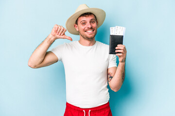 Young caucasian traveler man holding passport isolated on blue background feels proud and self confident, example to follow.