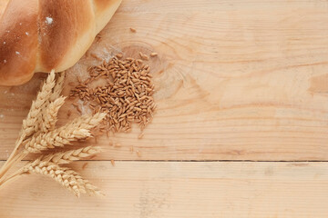 Wheat ears, grain, flour in a spoon, round bread,  on a light wooden board. Farm products,...