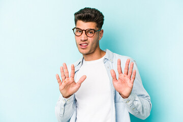 Young caucasian man isolated on blue background rejecting someone showing a gesture of disgust.