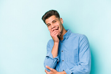 Young caucasian man isolated on blue background laughing happy, carefree, natural emotion.