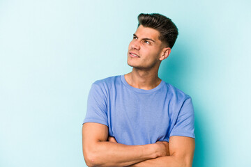 Young caucasian man isolated on blue background dreaming of achieving goals and purposes