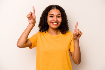 Young African American woman isolated on white background indicates with both fore fingers up...