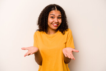 Young African American woman isolated on white background makes scale with arms, feels happy and confident.