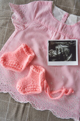 ultrasound picture, pink dress and knitted booties. the concept of motherhood, new life, the birth of a baby