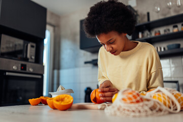 Young african american teenager slicing orange