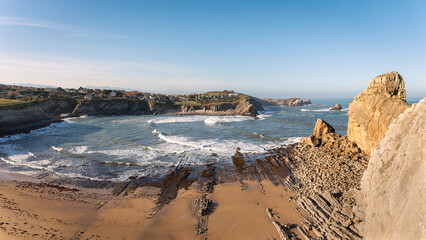 Beautiful panoramic view of Portio beach with its spectacular rock formations on the shore and the houses on the edge of the cliff, Costa Quebrada, Liencres, Cantabria, Spain