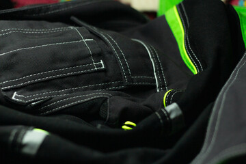 White stitching on black fabric. Texture of black working clothes with white stitching closeup, green reflective elements