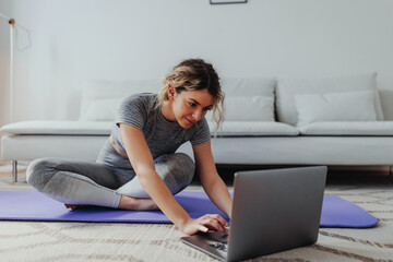 Young woman using computer while exercising