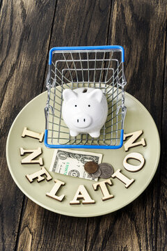 Inflation spelled in letters with american coins and banknotes and piggy bank on plate. Food inflation concept