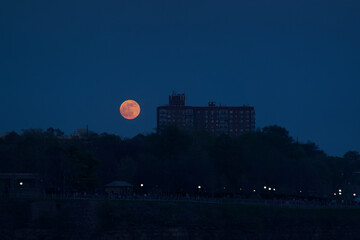 Blood moon rising over a building